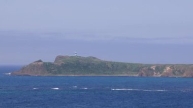 Güneşli bir günde Japonya Denizi 'ndeki kayalık ağaçsız adada küçük bir deniz feneri. Yüksek kalite 4k görüntü