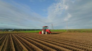 Sabah ışığında tarlada parlak kırmızı traktörün etrafında yavaş dönüyor. Yüksek kalite 4k görüntü