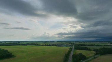 Fırtına kara bulutlar yaklaşırken yeşil tarlaların ve çiftliklerin üzerinden uçuyorlar. Yüksek kalite 4k görüntü