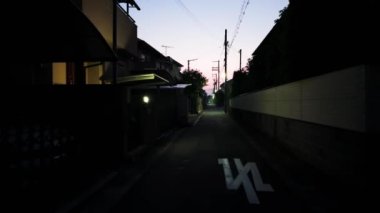 Japon banliyösündeki evlerin yanındaki karanlık yolda gün doğumu yürüyüşü. Yüksek kalite 4k görüntü