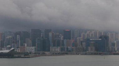 Hong Kong - 8 Ağustos 2023 Victoria Limanı 'ndaki gökdelenlerin üzerine gece ışıklar yanarken yağmur bulutları yağdı. Yüksek kalite 4k görüntü