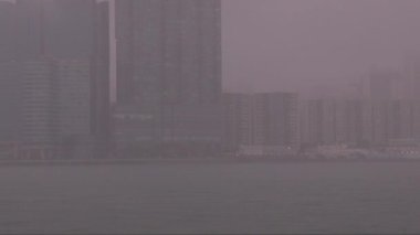 Yağmur damlaları, deniz kıyısındaki yüksek binalara yavaş çekimde sisli bir şekilde düşer. Yüksek kalite 4k görüntü