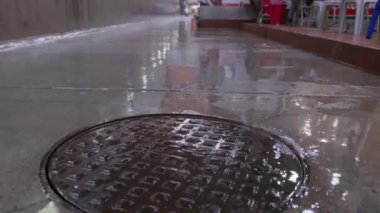 Hong Kong, 5 Ağustos 2023: Islak caddede su basıncıyla yükselen drenaj kapağındaki şiddetli yağmur. Yüksek kalite 4k görüntü
