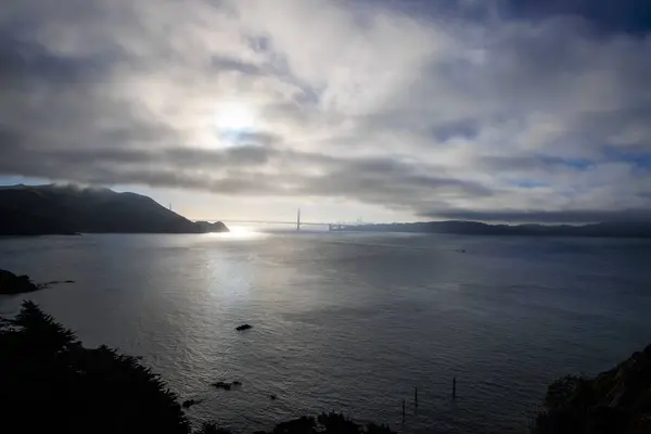 stock image Bright sun and dark clouds over coast with bridge and city in distance. High quality photo