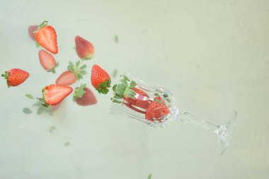 Fresh red strawberries fall from the glass. 