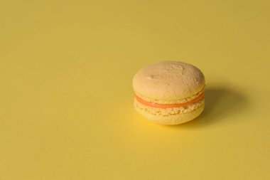A yellow macaron on a minimalistic yellow background.
