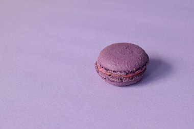 A purple macarons on a minimalistic purple background. 