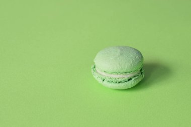 a green macarons on a minimalistic green background. 