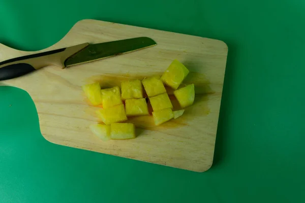 stock image slices of yellow watermelon in wooden plate. yellow watermelon cuts in green background