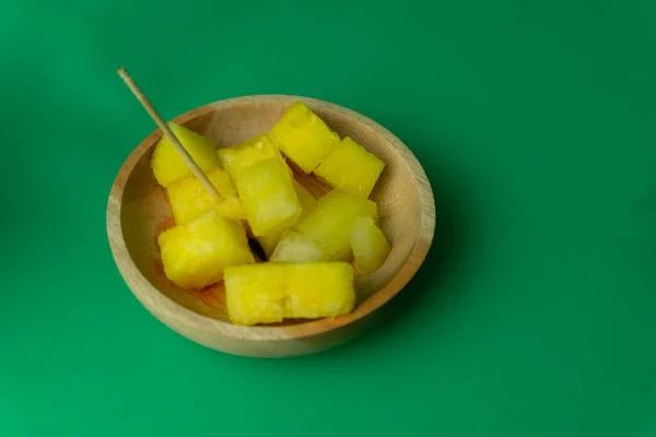 slices of yellow watermelon in wooden plate. yellow watermelon cuts in green background