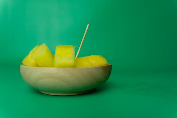 slices of yellow watermelon in wooden plate. yellow watermelon cuts in green background