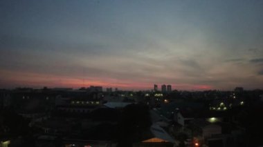 Şehrin arkasında gün batımının süresi doluyor. Endonezya, Medan 'daki otel penceresinden gün batımı manzarası çok güzel.