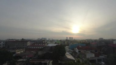 Şehrin arkasında gün batımının süresi doluyor. Endonezya, Medan 'daki otel penceresinden gün batımı manzarası çok güzel.