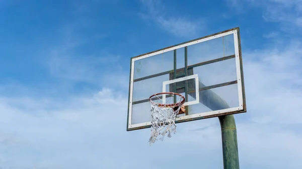 Low angle view of basketball ring on sky background. Outdoor basketball hoop. Net and rim