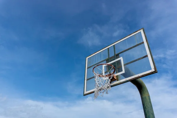 Low angle view of basketball ring on sky background. Outdoor basketball hoop. Net and rim