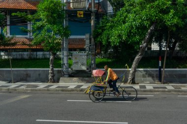 Surabaya, Endonezya - 18 Kasım 2021: Caddeden geçen bir triportör şoförü. Endonezya yerel taşımacılığı 