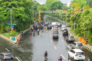 Surabaya, Endonezya - 18 Kasım 2021: Endonezya 'daki Darmo Caddesi' nden arabalar ve motosikletler geçiyor. Yağmurdan sonra ıslak sokak