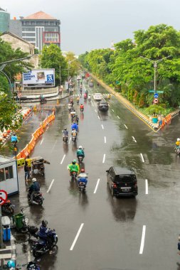 Surabaya, Endonezya - 18 Kasım 2021: Endonezya 'daki Darmo Caddesi' nden arabalar ve motosikletler geçiyor. Yağmurdan sonra ıslak sokak