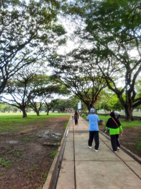 Banda Aceh, Endonezya - 27 Ekim 2023: Parkta koşan iki yaşlı Müslüman çift. Sabah yürüyüşü