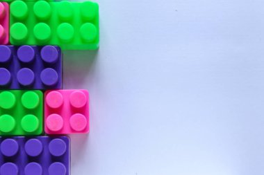 Beyaz arkaplandaki lego tuğlalarının üst açı görüntüsü. kopyalama alanı. İçerik veya metin için yeri olan renkli Lego blokları yığını
