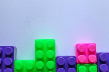 Beyaz arkaplandaki lego tuğlalarının üst açı görüntüsü. kopyalama alanı. İçerik veya metin için yeri olan renkli Lego blokları yığını