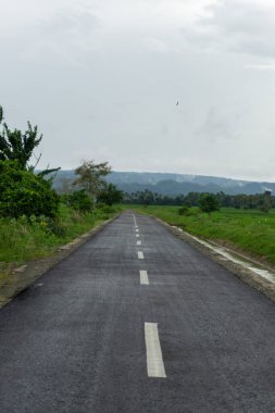 Arka planda dağ manzaralı boş asfalt yol. Aceh Besar, Endonezya 'da yol manzarası. 