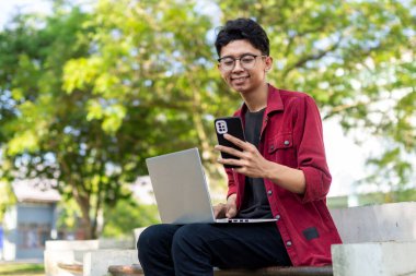 Genç Asyalı adam çalışırken gülümsüyor ve sabahları bilgisayar başında toplantı yapıyor. Evden çalışıyorum. Genç yaratıcı adam ekrana bakıyor.. 