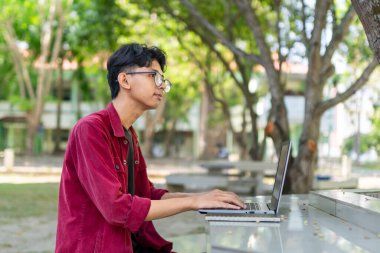 Genç Asyalı adam çalışırken gülümsüyor ve sabahları bilgisayar başında toplantı yapıyor. Evden çalışıyorum. Genç yaratıcı adam ekrana bakıyor.. 