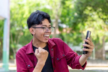 Asyalı adam telefonuna bakarken şaşırmış görünüyor. Heyecanlı ve mutlu bir adam cep telefonu arıyor.