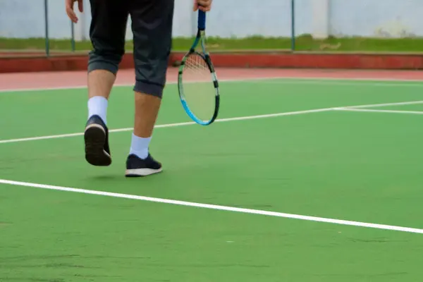Tenis kortunda oynayan siyah ayakkabılı tenisçi bacaklarını kapat. Açık sahada tenis oyuncusu