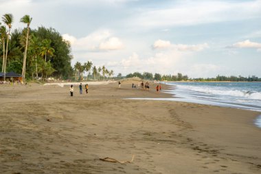 Meulaboh, Aceh sahilinde gün batımının keyfini çıkaran insanların silueti dramatik bulutlar ve altın gökyüzü..