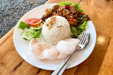 Pirinç, sebze ve krakerle servis edilen karabiber soslu tavuk. Asya Lezzetli Yemekler Ayam lada hitam. Tavuk göğsü kesimi ve karabiber sosuyla servis edilmiş..