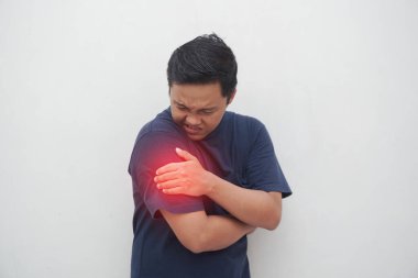 Kolu ağrıyan genç bir Asyalı beyaz tenli. Dirsek ağrısı çeken bir erkek. Omuz ağrısı.