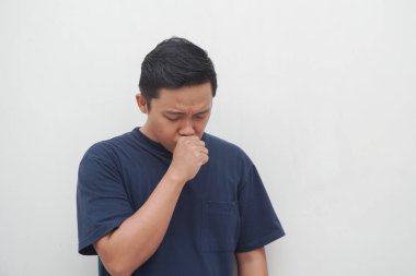 Genç Asyalı adam beyaz üzerine öksürüyor. Soğuk algınlığı belirtileri gösteren bir adam. Sağlıklı konsept.