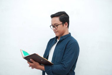  Okumak için kitap tutan gözlüklü mutlu Asyalı genç adam. Elinde kitaplarla gülümseyen genç Asyalı adam..