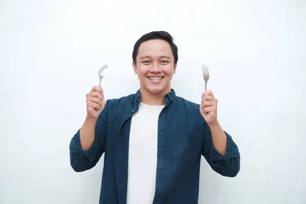 stock image Asian man holding spoon and fork with happy and excited expression. Healthy eating concept. Young man ready to eat.