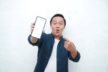 Mutlu Asyalı adam elinde mutlu ve heyecanlı bir ifadeyle boş bir akıllı telefon ekranı tutuyor. Mavi tişörtlü, gülümseyen ve reklam için beyaz cep telefonu ekranı gösteren genç bir Asyalı..