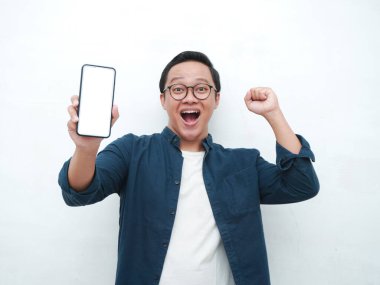 Mutlu Asyalı adam elinde mutlu ve heyecanlı bir ifadeyle boş bir akıllı telefon ekranı tutuyor. Mavi tişörtlü, gülümseyen ve reklam için beyaz cep telefonu ekranı gösteren genç bir Asyalı..