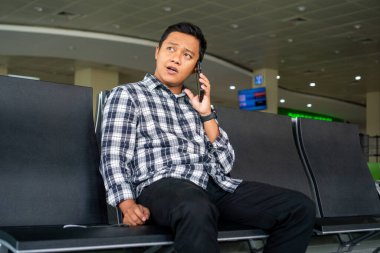 Erkek turist havaalanından kalkmayı beklerken telefonuyla arıyor. Havaalanı bekleme salonunda cep telefonu kullanan Asyalı bir adam..