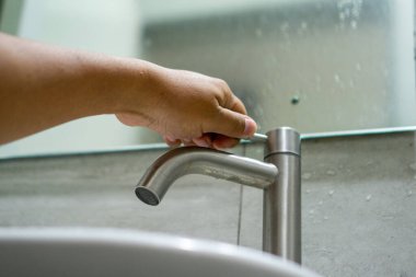 Banyodaki musluğu kapatıyorum. İnsan eli suyu idareli kullanmak için musluğu kapatır..