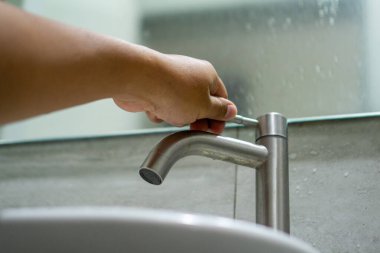 Banyodaki musluğu açıyorum. Adam eli su musluğunu açıyor..