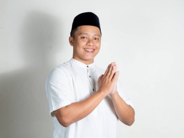 Müslüman Asyalı adam mutlu gülümsüyor ve Mübarek bayramını selamlıyor ve Ramazan ayını beyaz arka planda karşılıyor. Dindar insanlar ve İslami yaşam tarzı kavramı