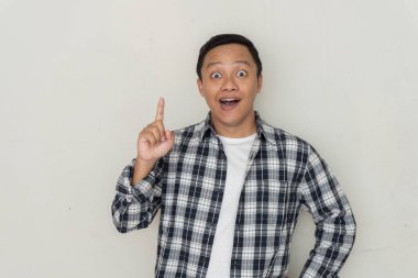 Çekici genç Asyalı adam gülümsüyor ve parmağını yana doğrultuyor. Boşluğu kopyala. 
