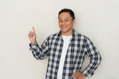 Çekici genç Asyalı adam gülümsüyor ve parmağını yana doğrultuyor. Boşluğu kopyala. 