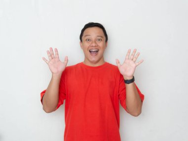 Şaşırmış ve heyecanlı bir ifadesi olan genç Asyalı bir adam, elleri havada ve ağzı beyaz arka planda açık. Kırmızı gömlekli adam şaşırmış görünüyor.