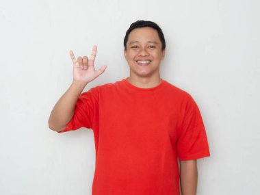 Young Asian man in red shirt smiles and makes a hand sign for 