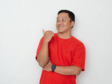 Happy Asian man in red shirt pointing his hand. Men shows surprised and amazed expression while pointing to a copy space clipart