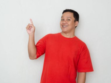 Kırmızı tişörtlü mutlu Asyalı elini gösteriyor. Erkekler bir kopyalama alanına işaret ederken şaşırmış ve şaşırmış ifadeler sergilerler