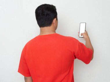 Elinde tuttuğu cep telefonuna bakan kırmızı tişörtlü bir adamın arka görüntüsü