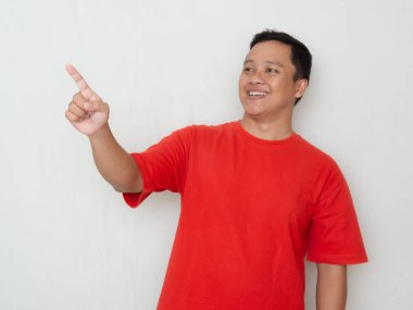 Kırmızı tişörtlü mutlu Asyalı elini gösteriyor. Erkekler bir kopyalama alanına işaret ederken şaşırmış ve şaşırmış ifadeler sergilerler